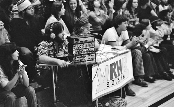 Students broadcasting form the WRHR table at a sporting event in the 1970s